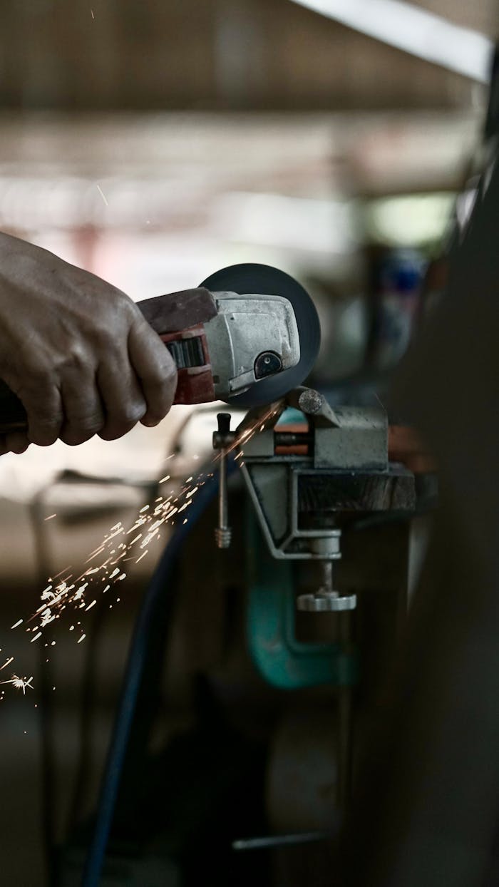 Close-up of hands using an angle grinder on metal with sparks flying.